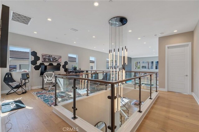 hall featuring an upstairs landing, light wood-type flooring, recessed lighting, baseboards, and a desk