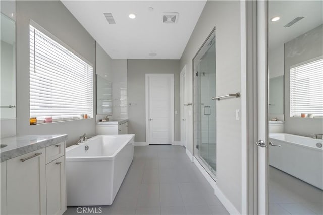 bathroom with a shower stall, tile patterned floors, vanity, and a freestanding tub