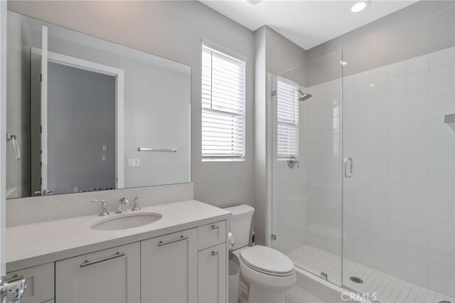 bathroom with a stall shower, toilet, and vanity