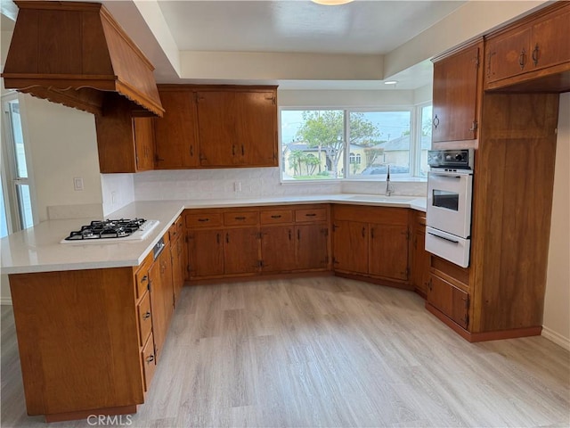 241 N 16th St N, Montebello, CA 90640 - kitchen with white appliances, light wood finished floors, a warming drawer, a sink, and brown cabinets