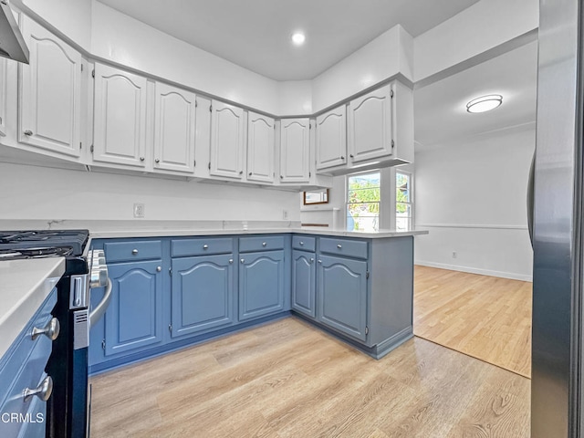 kitchen featuring stainless steel appliances, light wood finished floors, light countertops, blue cabinetry, and a peninsula