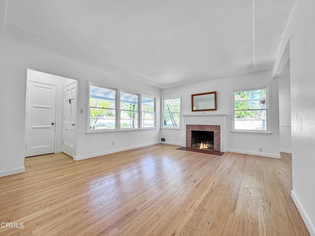 unfurnished living room featuring light wood finished floors, baseboards, and a brick fireplace