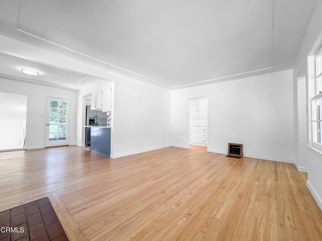 unfurnished living room featuring light wood-type flooring and baseboards