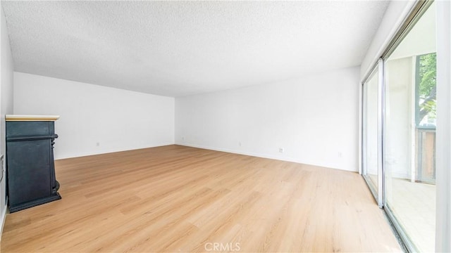 unfurnished living room with light wood-style flooring and a textured ceiling