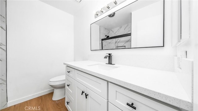 full bath with toilet, baseboards, vanity, wood finished floors, and a marble finish shower