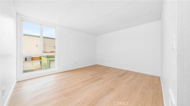 empty room with wood finished floors, baseboards, and a textured ceiling