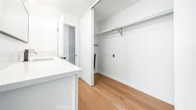 laundry room featuring a sink, light wood-style flooring, and baseboards