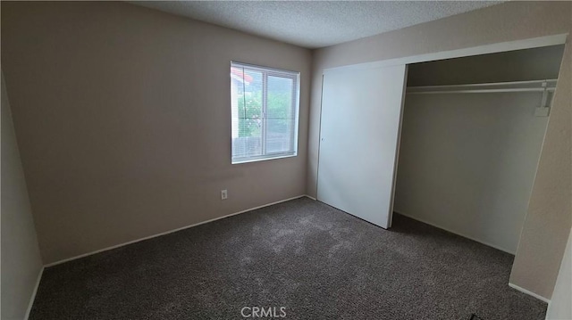 unfurnished bedroom with dark colored carpet, a textured ceiling, and a closet