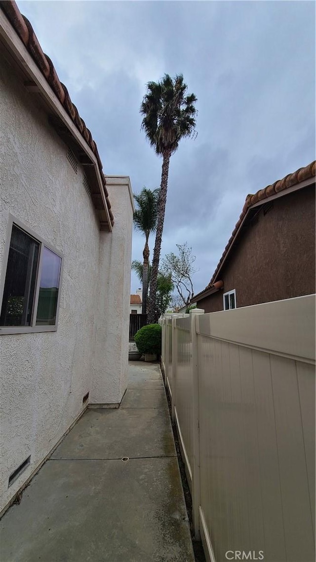 view of home's exterior with stucco siding, fence, a patio area, and a tiled roof