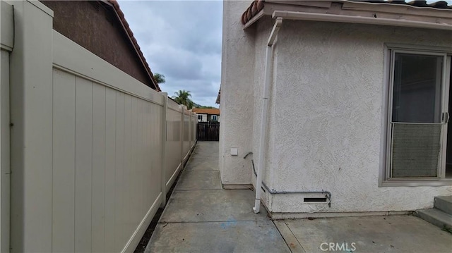 view of side of home featuring fence, stucco siding, and a patio area