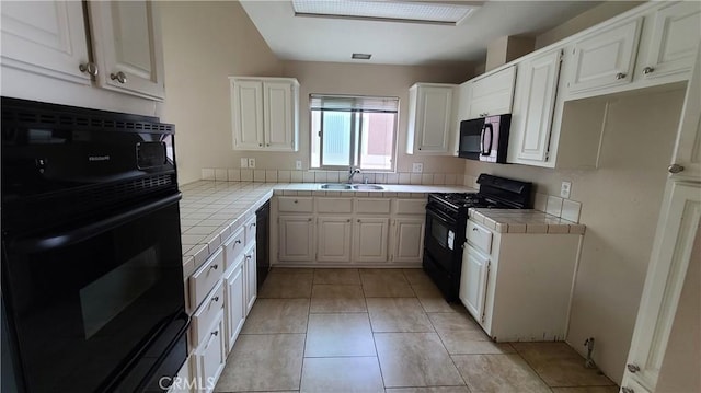 kitchen with tile counters, black appliances, a sink, white cabinetry, and decorative backsplash