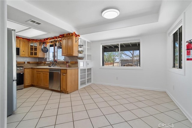 kitchen featuring stainless steel appliances, tasteful backsplash, plenty of natural light, and brown cabinetry