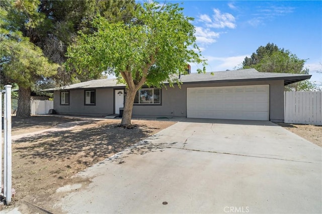 ranch-style home with fence, a garage, concrete driveway, and stucco siding