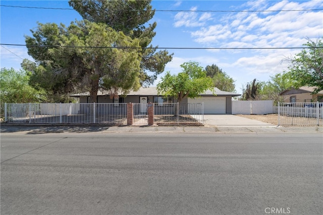 single story home with concrete driveway, a fenced front yard, and an attached garage
