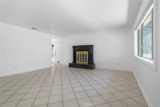 unfurnished living room with a high end fireplace and light tile patterned floors