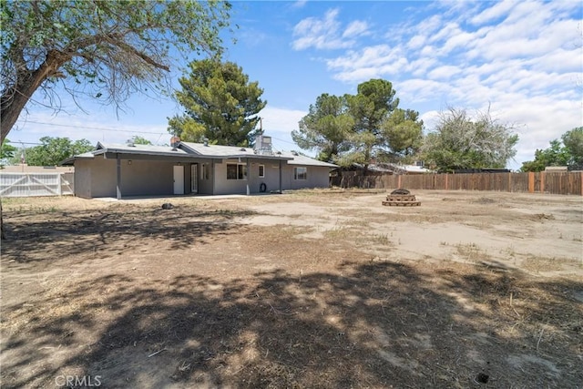 back of house with a fire pit, fence, an attached carport, and stucco siding
