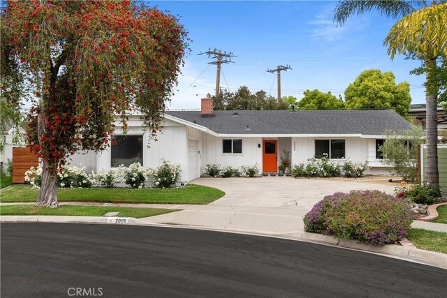 ranch-style home with driveway, a chimney, an attached garage, and roof with shingles