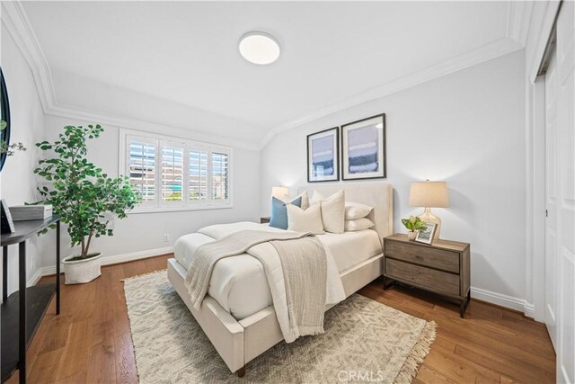 bedroom featuring ornamental molding, baseboards, and wood finished floors