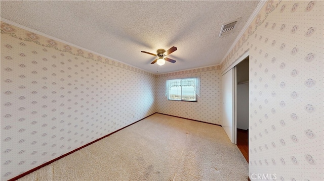 279 White Oak Rd, Lake Elsinore, CA 92530 - unfurnished bedroom with ornamental molding, a closet, wallpapered walls, a textured ceiling, and light colored carpet
