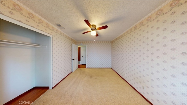 279 White Oak Rd, Lake Elsinore, CA 92530 - unfurnished bedroom featuring ornamental molding, a textured ceiling, a closet, wallpapered walls, and carpet