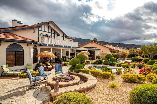 6723 Sycamore Ln, Palmdale, CA 93551 - back of property featuring a balcony, a patio area, an outdoor fire pit, stucco siding, and a mountain view