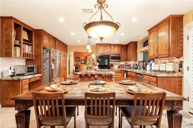 6723 Sycamore Ln, Palmdale, CA 93551 - kitchen with stainless steel appliances, a sink, arched walkways, a kitchen island, and brown cabinets