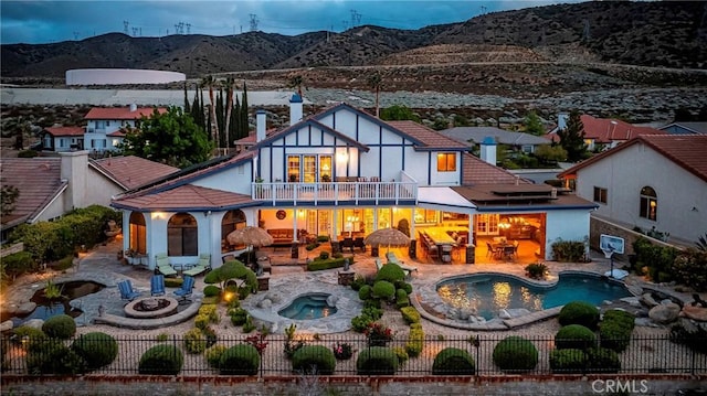 6723 Sycamore Ln, Palmdale, CA 93551 - back of house featuring an in-ground hot tub, a balcony, an outdoor fire pit, a mountain view, and a fenced backyard
