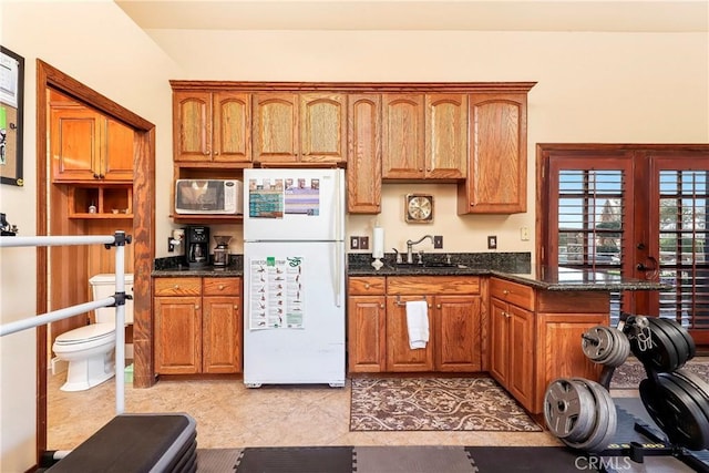 6723 Sycamore Ln, Palmdale, CA 93551 - kitchen featuring white appliances, a sink, brown cabinetry, dark stone counters, and light tile patterned flooring