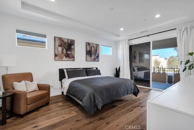 bedroom featuring access to outside, wood finished floors, a tray ceiling, recessed lighting, and baseboards