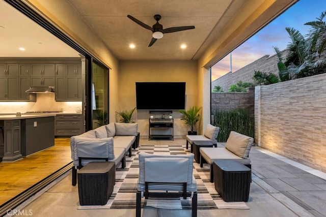 view of patio / terrace featuring an outdoor living space with a fireplace, fence, and ceiling fan