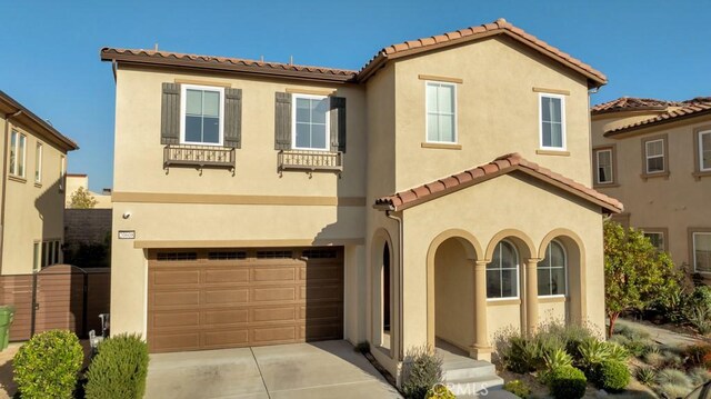 mediterranean / spanish home with an attached garage, stucco siding, and a tile roof