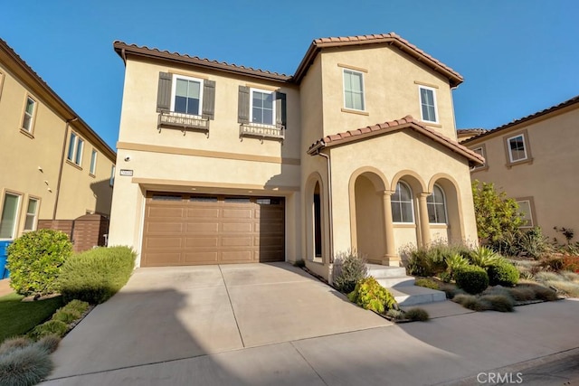mediterranean / spanish house featuring a garage, a tiled roof, driveway, and stucco siding