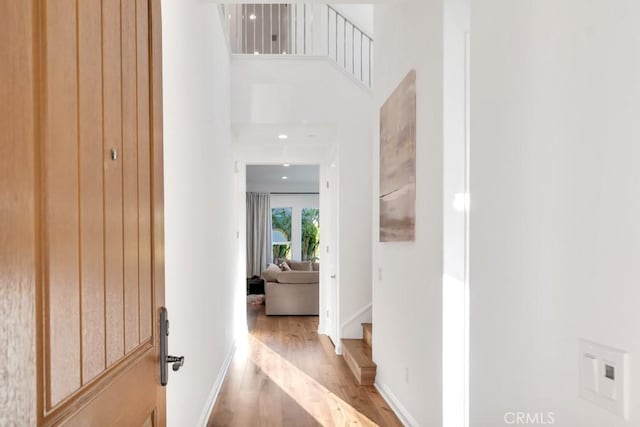 corridor with wood finished floors, baseboards, and stairway