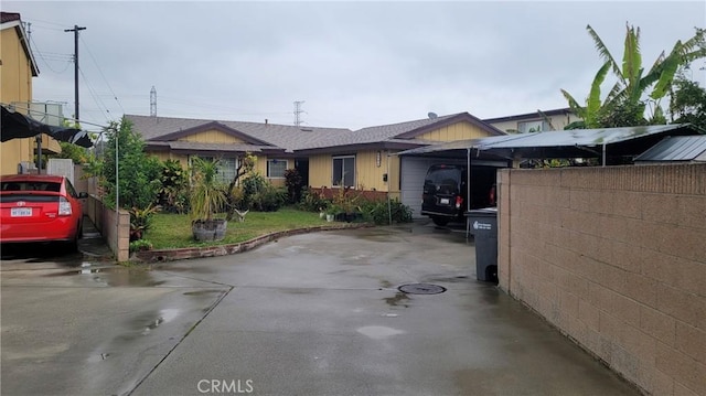 view of front facade featuring concrete driveway and fence