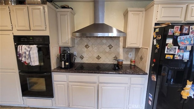 kitchen featuring black appliances, wall chimney range hood, tasteful backsplash, dark stone counters, and white cabinets