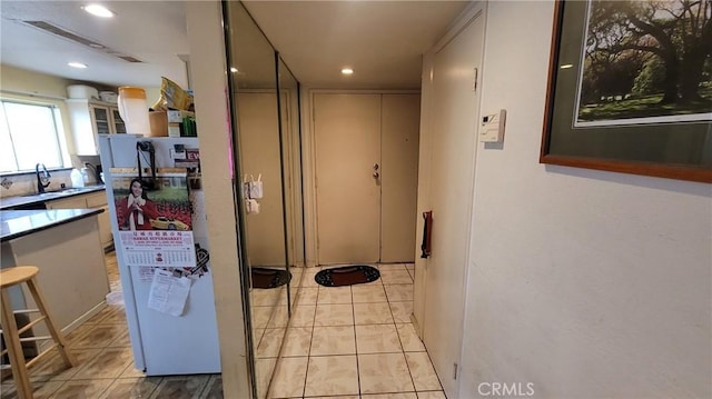 hallway featuring a sink, recessed lighting, and light tile patterned floors
