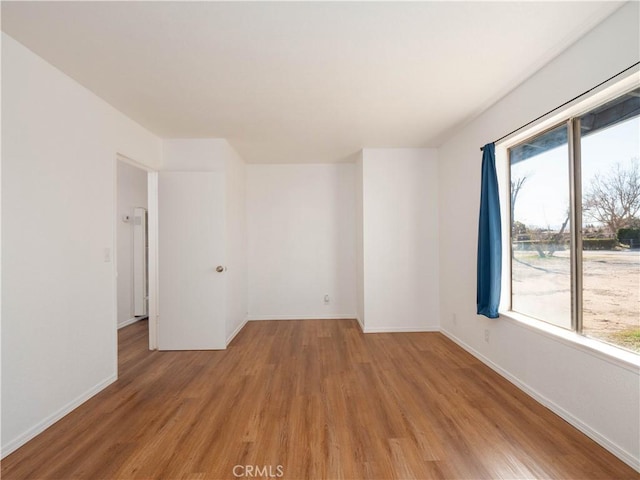 empty room with light wood-style flooring, plenty of natural light, and baseboards