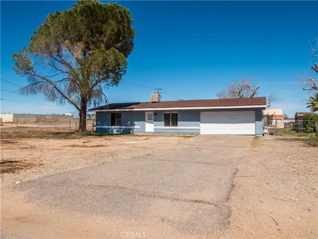 view of front of property featuring a garage, fence, driveway, and stucco siding