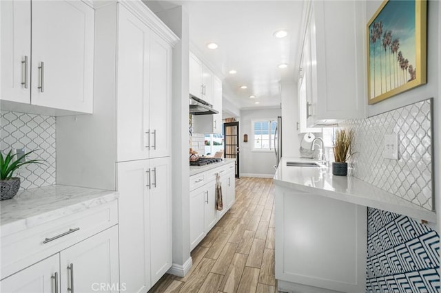 1742 Dixon St, Redondo Beach, CA 90278 - kitchen featuring a sink, under cabinet range hood, light wood-style flooring, backsplash, and white cabinets