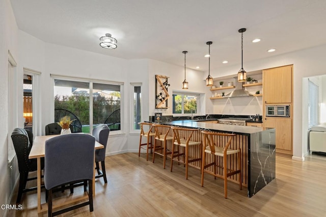 800 Coronado Pl, Oxnard, CA 93030 - kitchen featuring stainless steel microwave, dark countertops, light wood finished floors, open shelves, and a kitchen bar