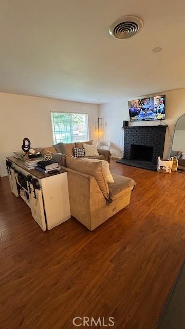 living area featuring a brick fireplace and wood finished floors