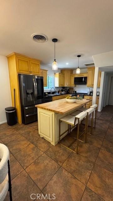 kitchen with black fridge with ice dispenser, butcher block counters, a kitchen island, hanging light fixtures, and exhaust hood