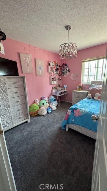 bedroom with carpet floors, a textured ceiling, and a chandelier