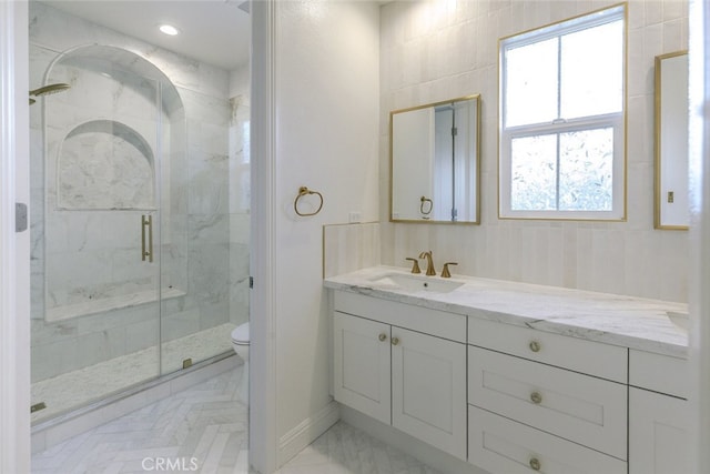 full bathroom featuring toilet, vanity, and a marble finish shower