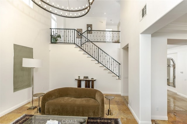 stairs with a towering ceiling, a chandelier, crown molding, and baseboards