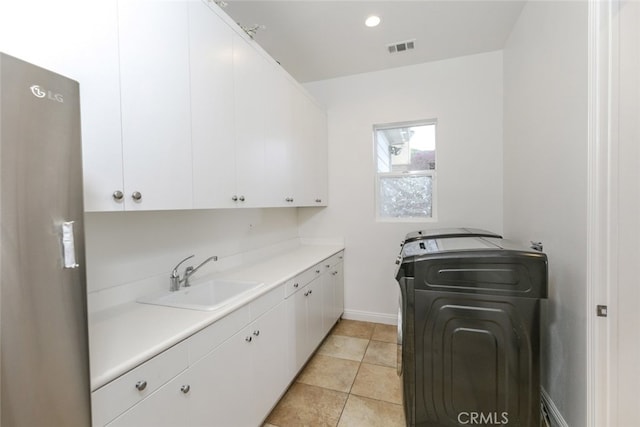 washroom featuring cabinet space, washer / dryer, baseboards, and light tile patterned flooring