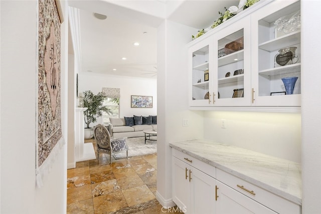 bar area with light stone finish floors, ornamental molding, and recessed lighting