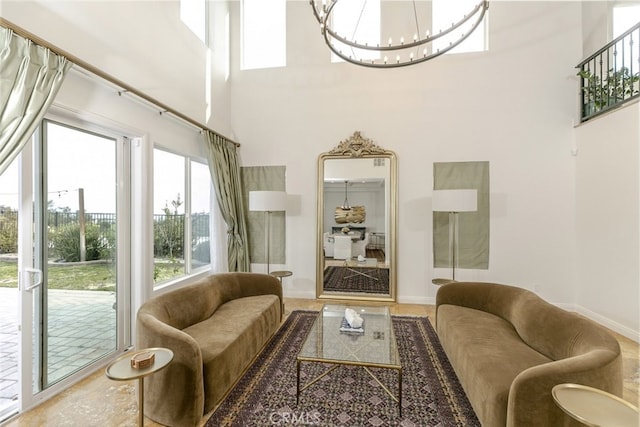 living room with a high ceiling, a chandelier, and baseboards