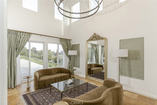 living room featuring a chandelier, baseboards, and a towering ceiling