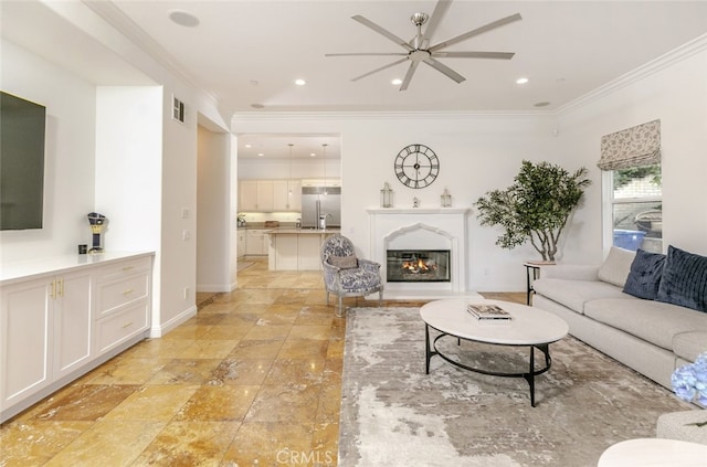 living room featuring ceiling fan, ornamental molding, a glass covered fireplace, baseboards, and recessed lighting